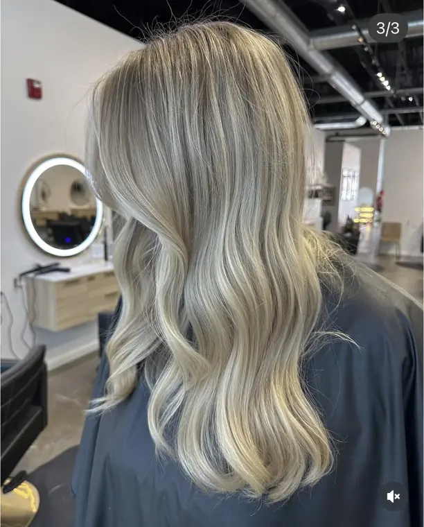 Long bright blonde hair with soft waves and dimensional highlights.